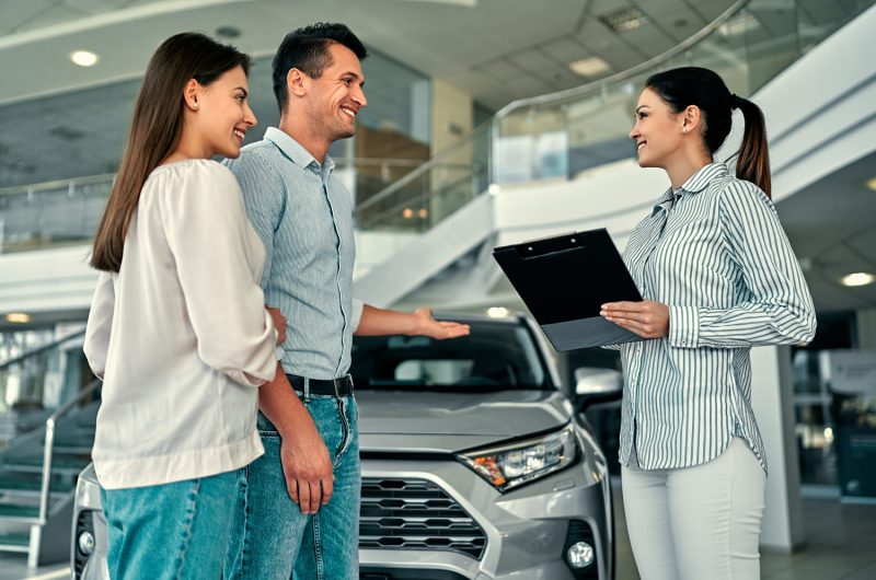 Pareja concesionario viendo coches con agente